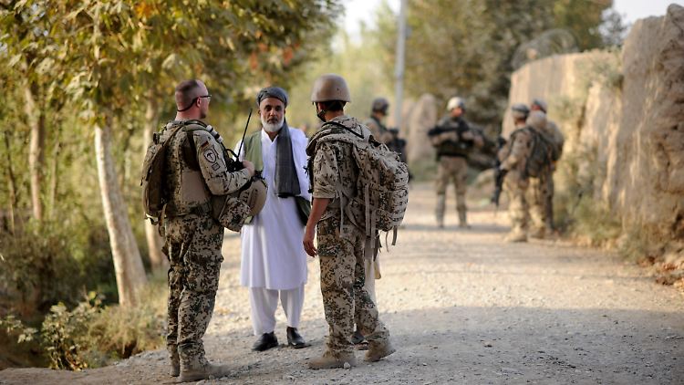 Der Uniformierte zur rechten Seite ist eine Ortskraft: Er hilft dem Bundeswehrsoldaten links als Dolmetscher im Gespräch mit einem Afghanen nahe Kundus.