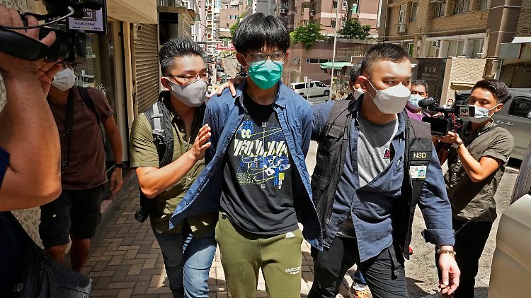 Ein Student der Universität Hongkong wird nach einer Hausdurchsuchung von zwei Polizeibeamten eskortiert.