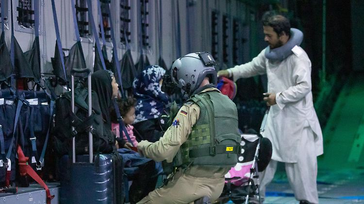 Ein Ladungsmeister der Bundeswehr hilft Afghanen beim Anschnallen im Transportflugzeug A400M am Flughafen von Kabul.