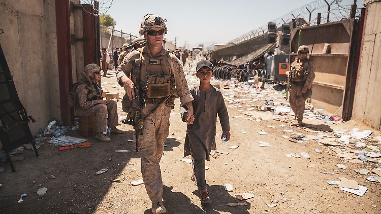 Ein Marine bringt ein Kind am Flughafen in Kabul in Sicherheit. Tausende Menschen stehen noch Ausreiselisten der Nato-Staaten. 
