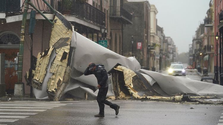 New Orleans: Ein Mann geht an einem Teil des Daches vorbei, das von einem Gebäude weggeblasen wurde.
