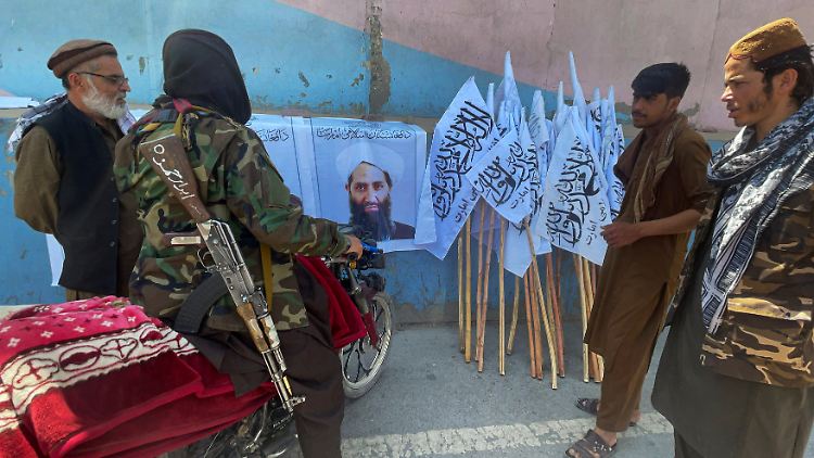 Taliban-Anhänger begutachten ein Plakat mit dem Konterfei Achundsadas.