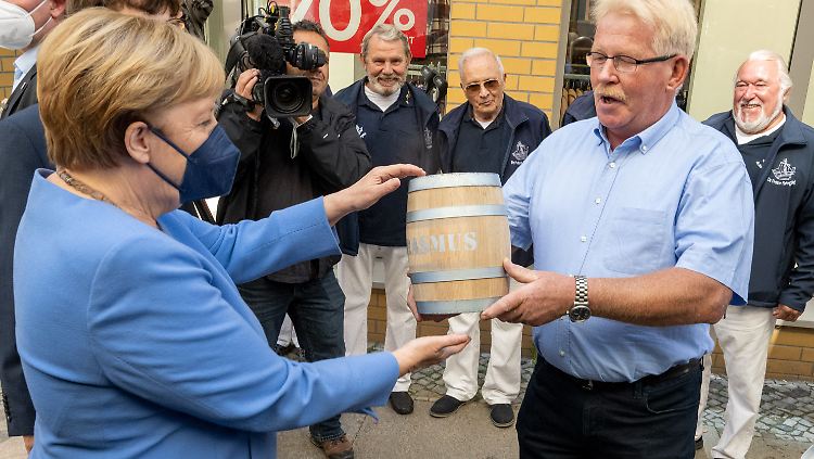 Merkel erhält vom Fischhändler Rasmus eine der Spezialitäten der Hansestadt - den Bismarck-Hering. Dessen "Erfindung" vor 150 Jahren feiert die Stadt am kommenden Wochenende.