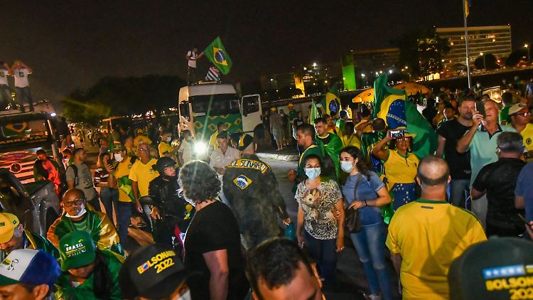 Mit LKW durchbrechen Demonstranten eine Polizeiblockade und protestieren auf einer gesperrten Straße.