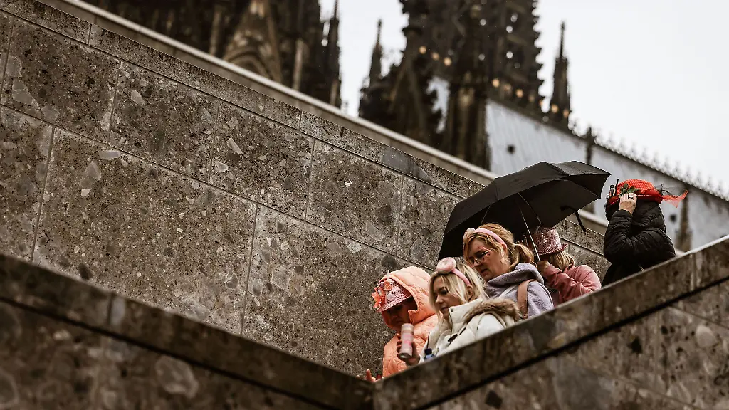 Karnevalistinnen-feiern-im-Februar-2024-mit-Regenschutz-am-Koelner-Dom