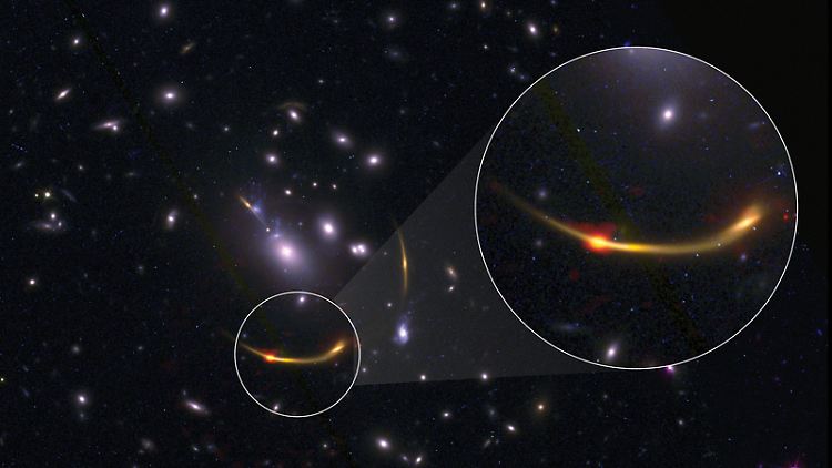 Bild des Galaxienhaufens MACSJ 0138. Am hellen orangeroten Punkt, der auf kalten Staub hinweist, können Forscher die Menge des kalten Wasserstoff-Gases bestimmen, das für die Bildung von Sternen erforderlich ist.