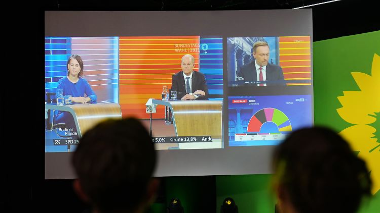 Auf der Wahlparty der Grünen sind auf einem Bildschirm Baerbock, Lindner und Scholz zu sehen - zwei von ihnen vertreten "Parteien, die gegen den Status-Quo Wahlkampf gemacht haben", wie der FDP-Chef es formuliert.