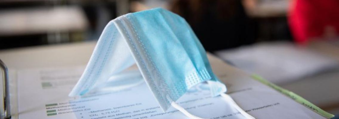Eine Medizinische Maske liegt im Schulunterricht auf einem Tisch. Foto: Matthias Balk/dpa/Symbolbild
