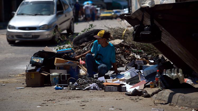 In Valencia sucht ein Mann im Müll nach weggeworfenem Essen.