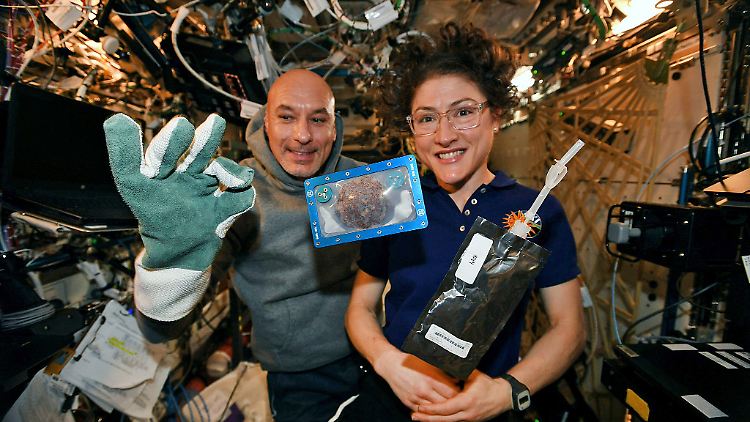 US-Astronautin Christina Koch und ihr Kollege Luca Parmitano aus Italien zeigen einen Keks, den sie auf der ISS gebacken haben.