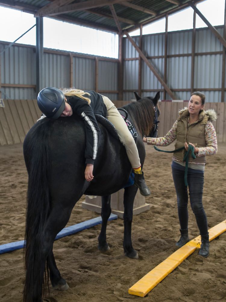 Bei der Pferdetherapie legt sich Karen A. auf das Pferd, das von Therapeutin Rebecca Böde gehalten wird.