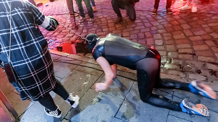 Eine Domina führt ihren Sklaven an einer Hundeleine auf St. Pauli durch die Herbertstraße.
