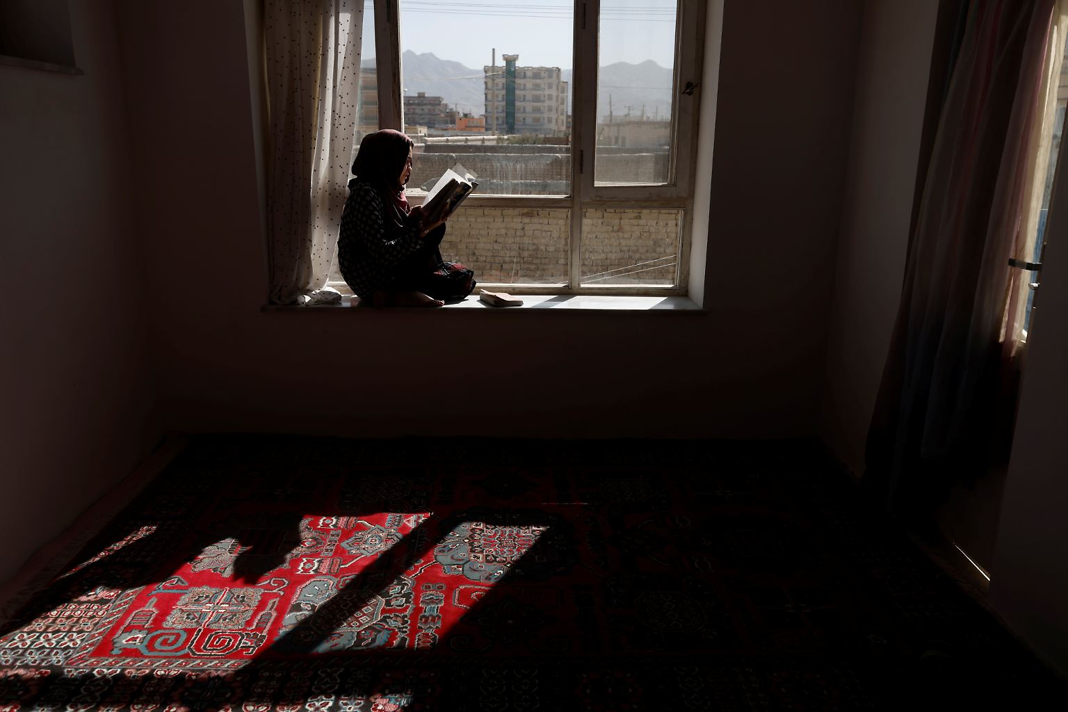Um ihre Tage auszufüllen und sich zu beschäftigen, sitzt Hawa an einem Fenster im Haus ihrer Familie in Kabul und liest ein Buch.