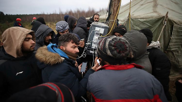 Auf belarussischer Seit laden Flüchtlinge ihre Mobiltelefone auf.