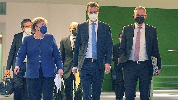 Kanzlerin Angela Merkel schreitet mit NRW-Ministerpräsident Henrik Wüst und Berlins Regierendem Bürgermeister Michael Müller zur Pressekonferenz.
