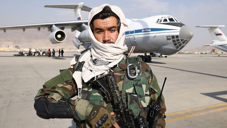 Ein Taliban-Mitglied vor einem russischen Flugzeug, das Hilfsgüter nach Kabul bringt.