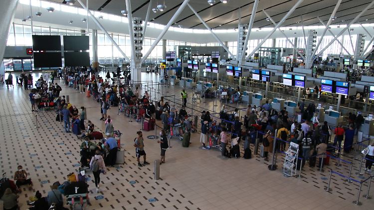 Reisende stehen am Flughafen in Kapstadt in langen Schlangen an den wenigen Schaltern an, die überhaupt noch offen sind.