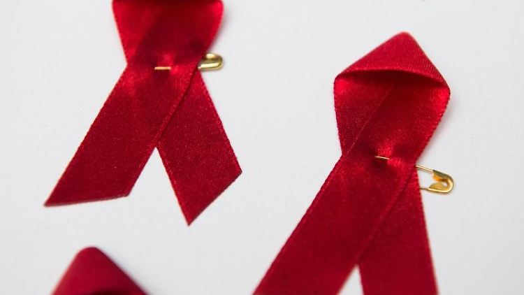 Rote Schleifen, das Symbol für die Solidarität mit HIV-Infizierten, liegen auf einem Tisch. Foto: Lukas Schulze/dpa/Symbolbild