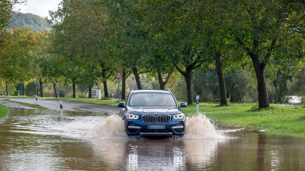 Ein-PKW-faehrt-durch-einen-von-der-Mosel-ueberfluteten-Strassenabschnitt-bei-Lieser-Archiv