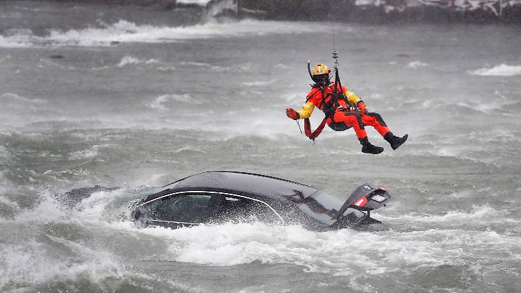 Bei eisiger Kälte und leichtem Schneefall lässt der Helikopter den Retter an einem Seil zum verunglückten Auto herunter.