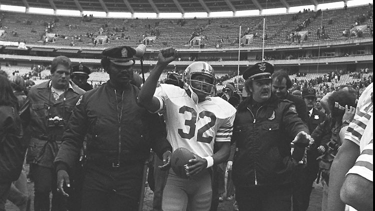 Nach seinem letzten Spiel wird O.J. Simpson von zwei Polizisten vom Platz eskortiert. 