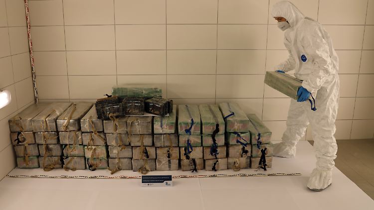 Ein Mitarbeiter der beteiligten Behörden stapelt Blöcke von Kokain.