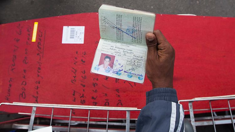 Ein nepalesischer Gastarbeiter zeigt den Reisepass eines Freundes, der 2013 als Arbeitsmigrant in Katar starb, neben dessen Sarg.