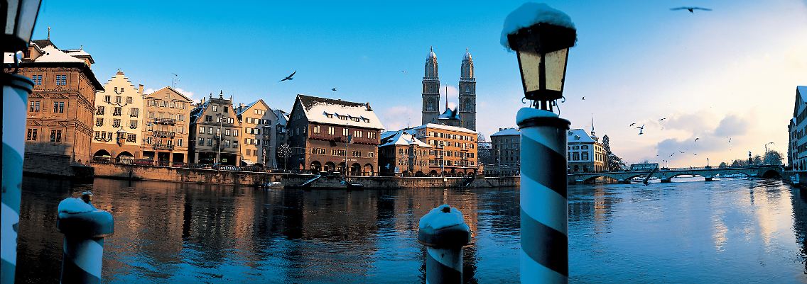Die Limmat fließt im Winter gemächlich wie immer - im Hintergrund ragen die beiden Türme des Großmünsters in den Himmel über Zürich.