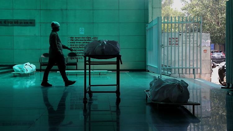 Corona-Tote in einem Krematorium in Neu Delhi: In den USA, Südafrika und Indien macht sich bei Versicherern und Rückversicherern im zweiten Jahr der Krise ein Anstieg der Sterbefälle bemerkbar.