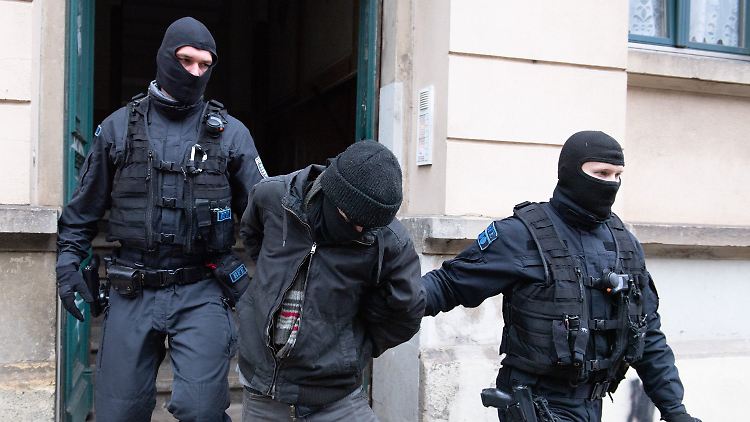 Polizisten führen bei einer Razzia in Dresden einen Tatverdächtigen aus einem Haus, nachdem es Drohungen gegen Sachsens Ministerpräsidenten Kretschmer gab.