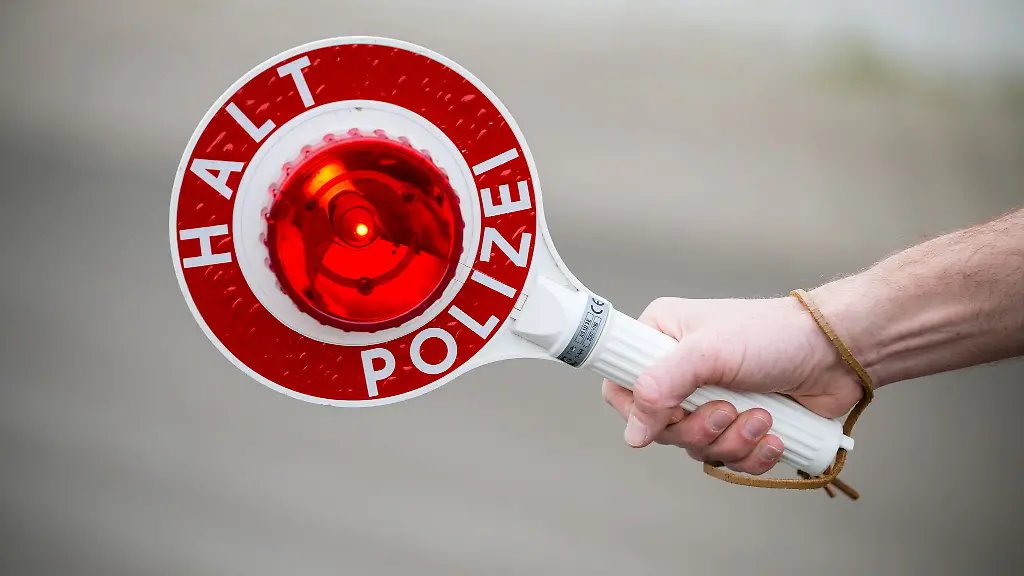 Ein-Polizist-haelt-eine-Kelle-die-zum-Anhalten-auffordert