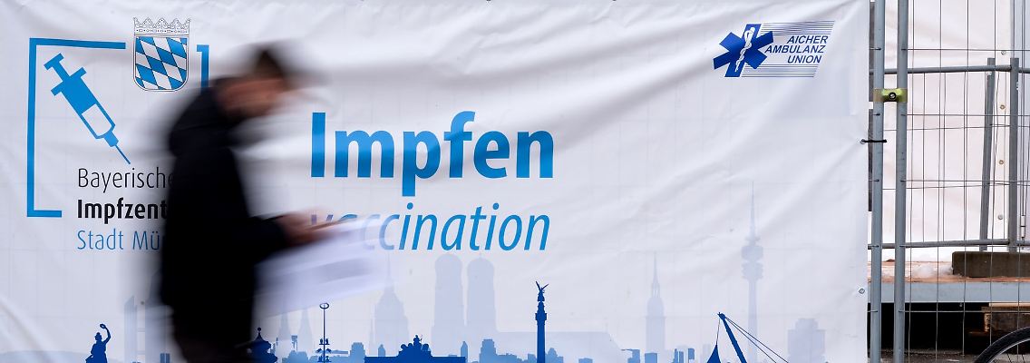 Ein Mann geht auf der Theresienwiese an einer Corona-Impfstation vorbei.