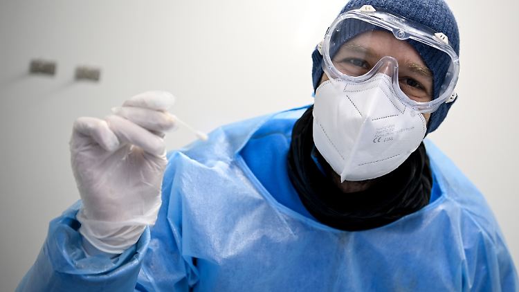 Oliver Müller, Arzt, hält ein Teststäbchen für die Entnahme einer Probe für einen PCR-Test beim Gesundheitsamt Neukölln in der Hand.