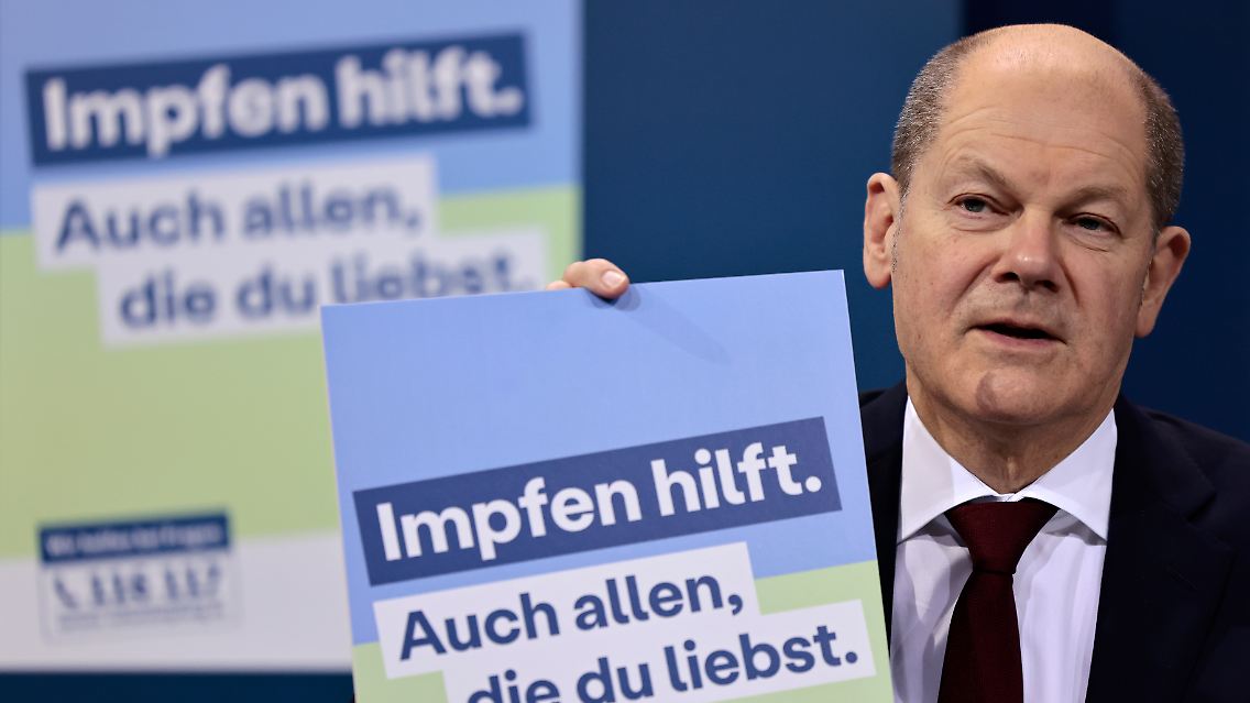 Bundeskanzler Scholz präsentiert ein Plakat für eine neue Impfkampagne.