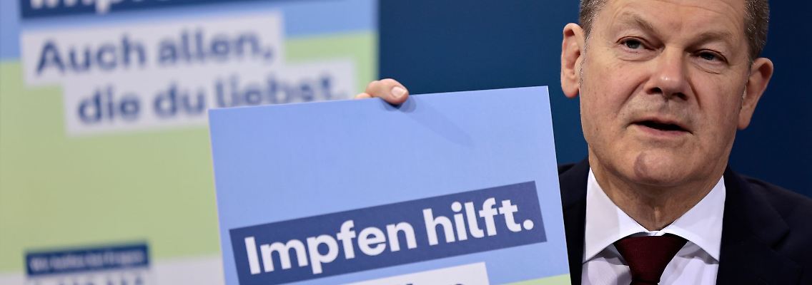 Bundeskanzler Olaf Scholz präsentiert ein Plakat aus der neuen Impfkampagne.