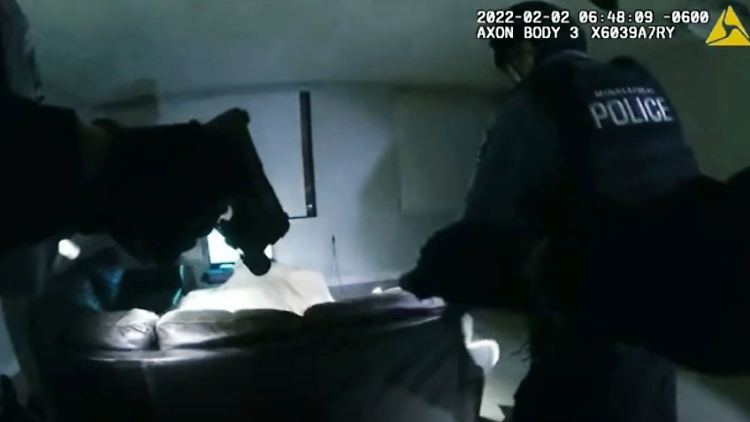 Unter dem Bettlaken befindet sich der Mann, der sich wenige Sekunden nach dem Hereinstürmen der Polizisten zu regen beginnt.