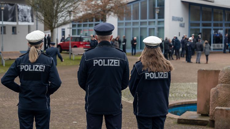 Polizisten stehen vor der Bruchwaldhalle und warten auf die Übertragung der Beisetzung des Polizeikommissars.