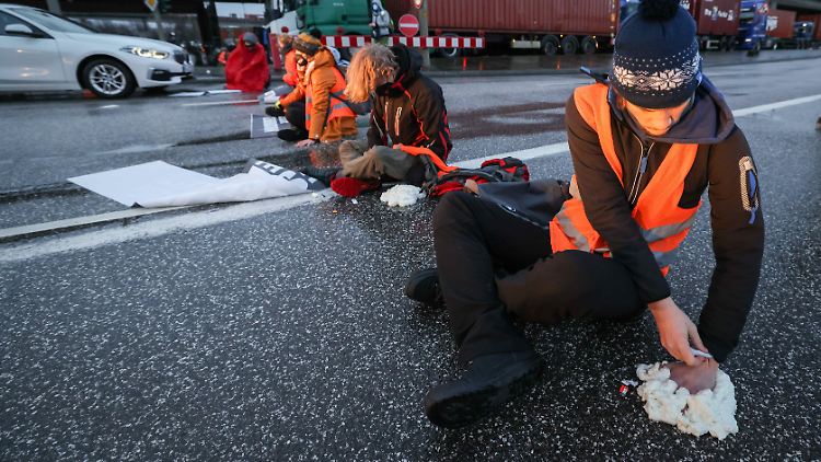 Die Demonstranten kleben sich an die Fahrbahn, um nicht so einfach davongetragen werden zu können.