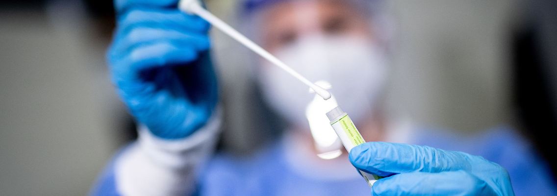 Eine medizinische Mitarbeiterin hält in einem Corona-Testzentrum ein Abstrichstäbchen in der Hand.