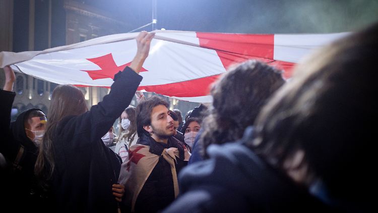 Demonstranten gegen den Ukraine-Krieg halten in Georgien ihre Landesfahne in die Luft.