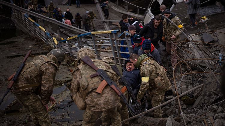 Ukrainische Soldaten helfen einem Mann im Rollstuhl, während Menschen versuchen, über den Fluss Irpin in den Außenbezirken von Kiew, Ukraine, zu fliehen.