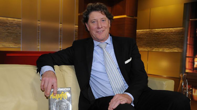 Schumacher, ein Buch und eine Couch in einem TV-Studio. 