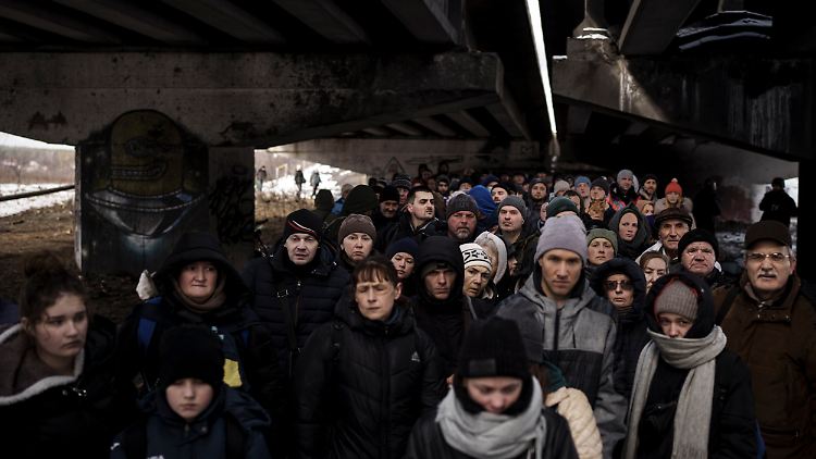 Ukrainer drängen sich unter einer zerstörten Brücke, als sie versuchen, über den Fluss Irpin in den Außenbezirken von Kiew, Ukraine, zu fliehen.