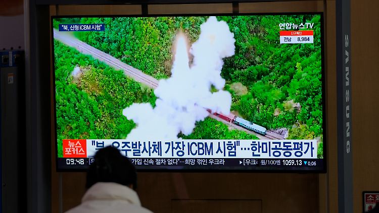 Eine Frau betrachtet einen Fernsehbildschirm in einem Bahnhof, auf dem eine Nachrichtensendung über Nordkoreas Raketen gezeigt wird.