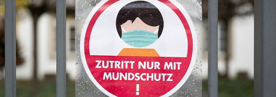 Ein Schild an einem Eingang weist auf das Tragen einer Maske hin.
