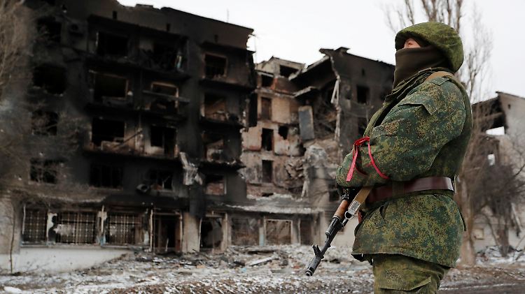 Ein Kämpfer der russischen Truppen vor einem zerstörten Wohnhaus in Volnovakha. Dem Kreml-Sprecher zufolge läuft der Einsatz wie vorgesehen.  