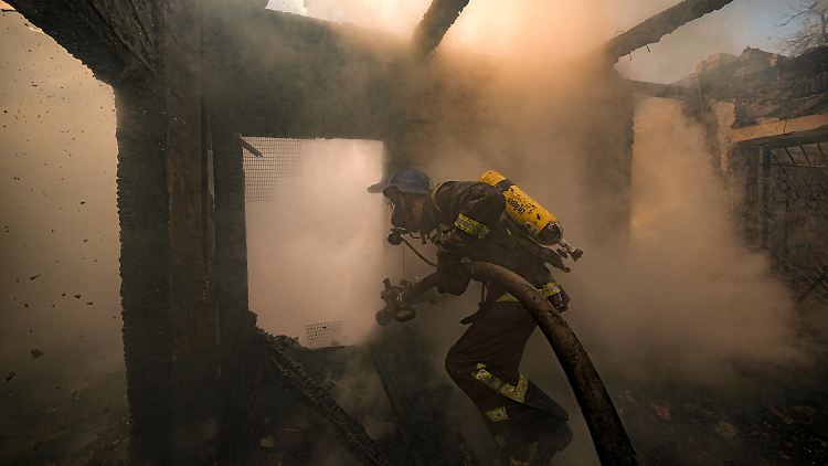 Ein ukrainischer Feuerwehrmann geht während der Löscharbeiten durch ein nach russischen Angriffen zerstörtes Haus in Kiew.