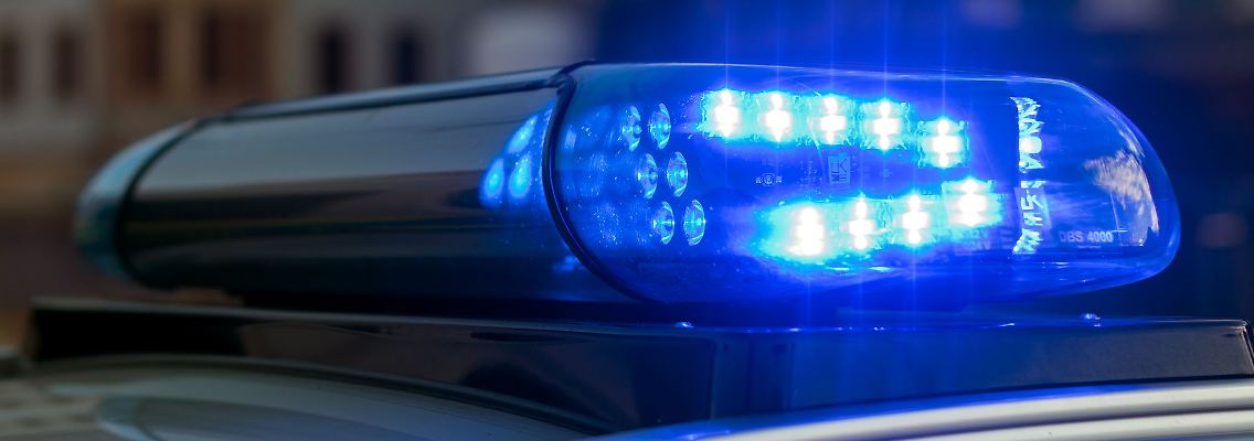 Das Blaulicht auf einem Fahrzeug der Polizei leuchtet in der Dunkelheit.