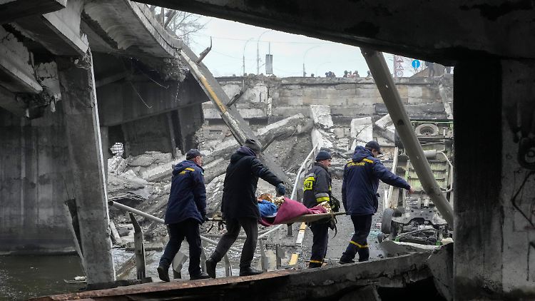 Helfer versuchen, eine verletzte Frau aus Mariupol über eine zerstörte Brücke in Sicherheit zu bringen.