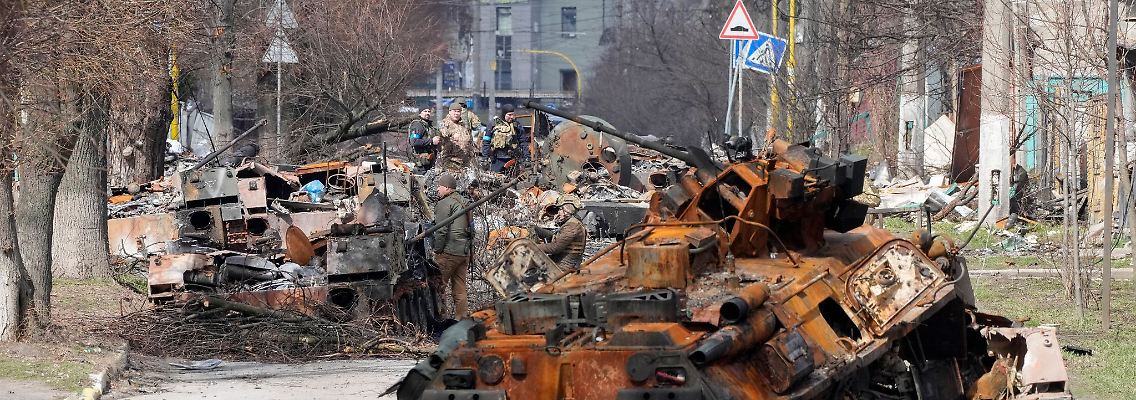 Ukrainische Soldaten untersuchen zerstörte russische Militärfahrzeuge in Butscha.